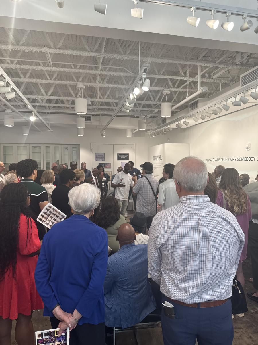 The opening reception attendees listening to an Exoneree story